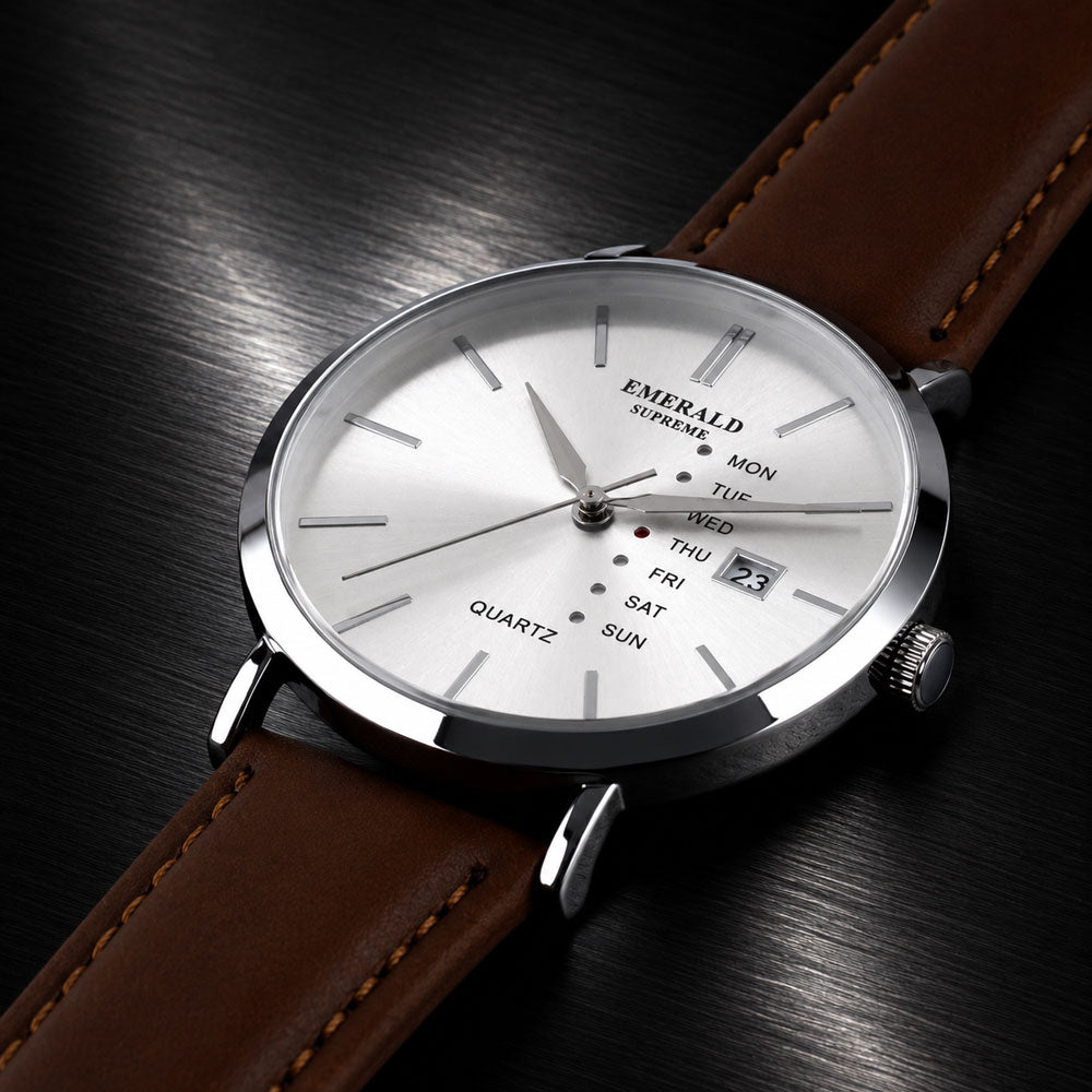 A close-up of an Emerald brand quartz watch with a silver-toned case, white dial, and brown leather strap, resting on a dark textured surface.