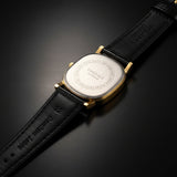 Watch with gold case and beige leather strap on a white background
