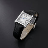 Black leather wristwatch with a white face and Roman numerals on a light gray background
