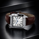 A Semald watch with a silver-toned rectangular case, white dial with black Roman numerals, and a brown leather strap, displayed on a dark reflective surface.