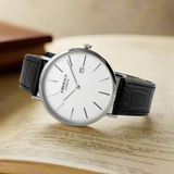 Wristwatch with black leather strap and white dial on a light gray background