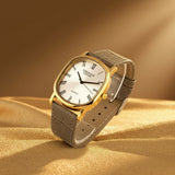 Wristwatch with gold case and gray leather strap on a white background