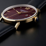 Luxury watch with gold case and black strap on a light gray background
