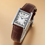 Watch with brown leather strap and white face on beige background